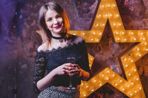 Person in black lace dress holding wine glass against illuminated star backdrop