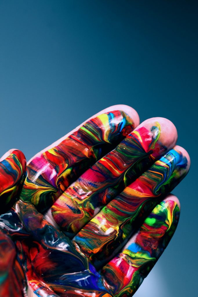 A hand, covered in paint of different colours in an amazing pattern