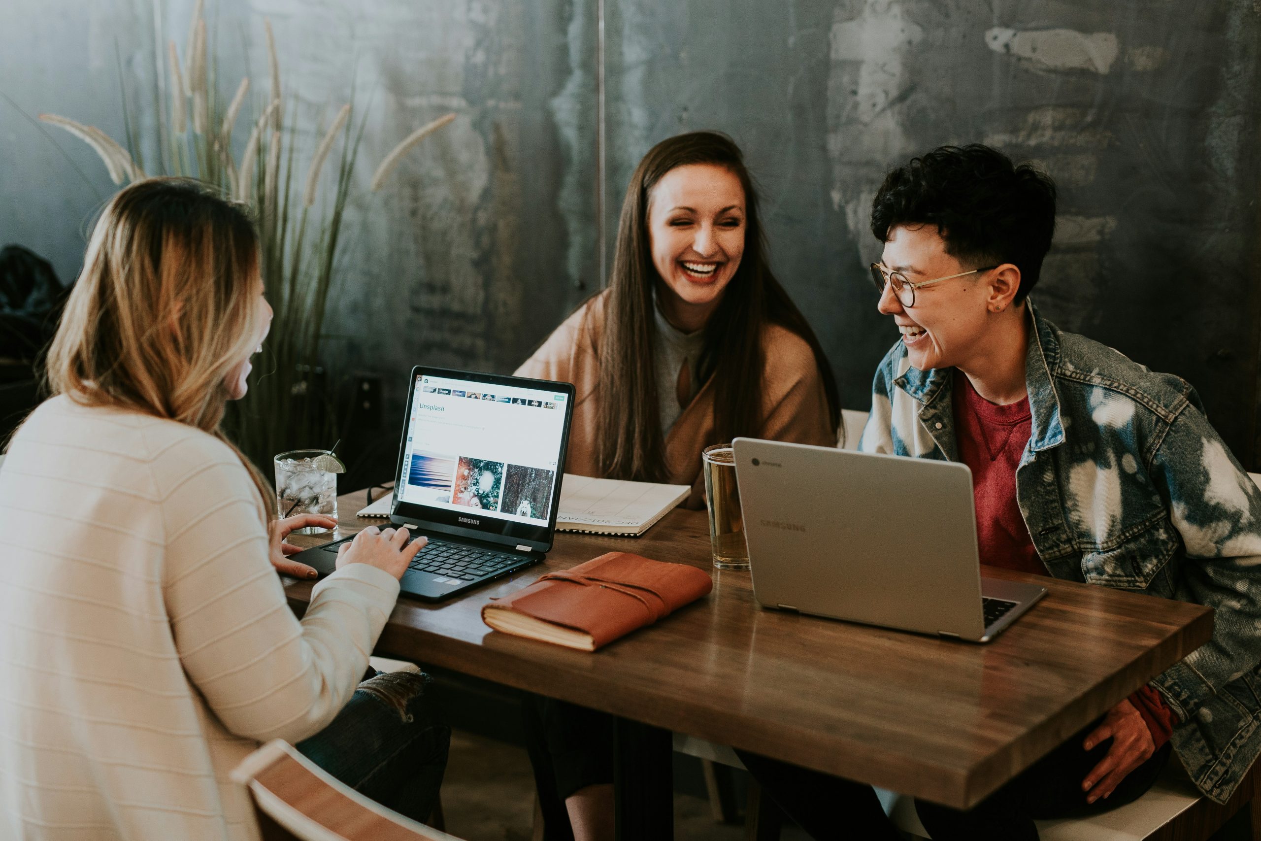 a group of people working round a table on their laptops