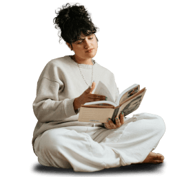 Person in casual white outfit sitting cross-legged while reading a book