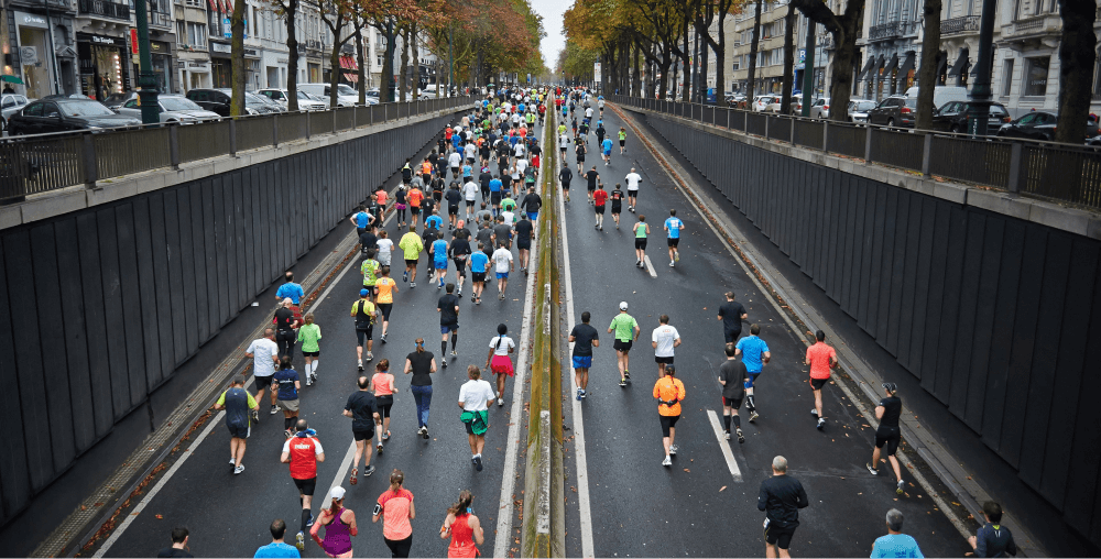 Aerial view of a city marathon with runners spread across a divided road lined with autumn trees and buildings