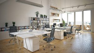 Modern office space with white desks, bookshelves, and natural light from balcony doors