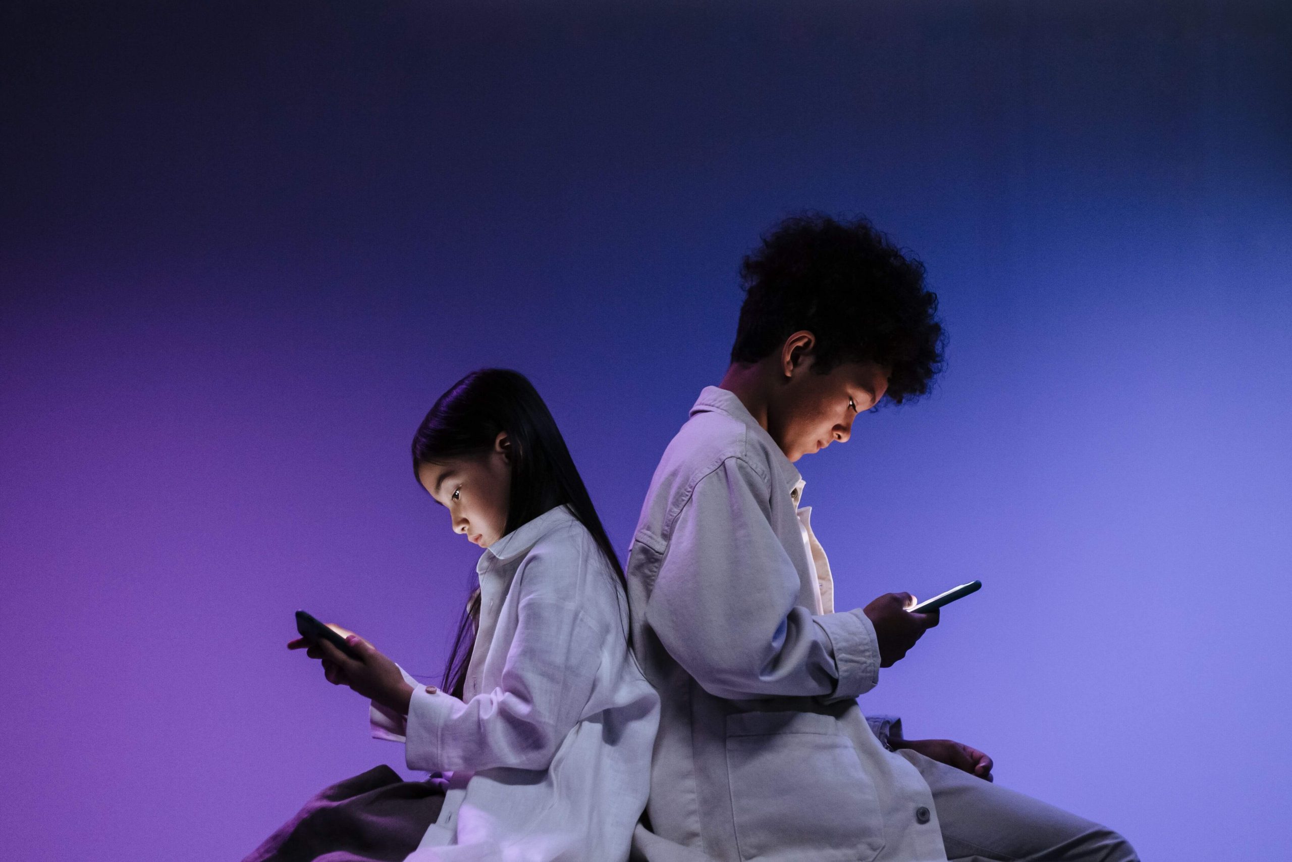 Two children sat staring at their phones
